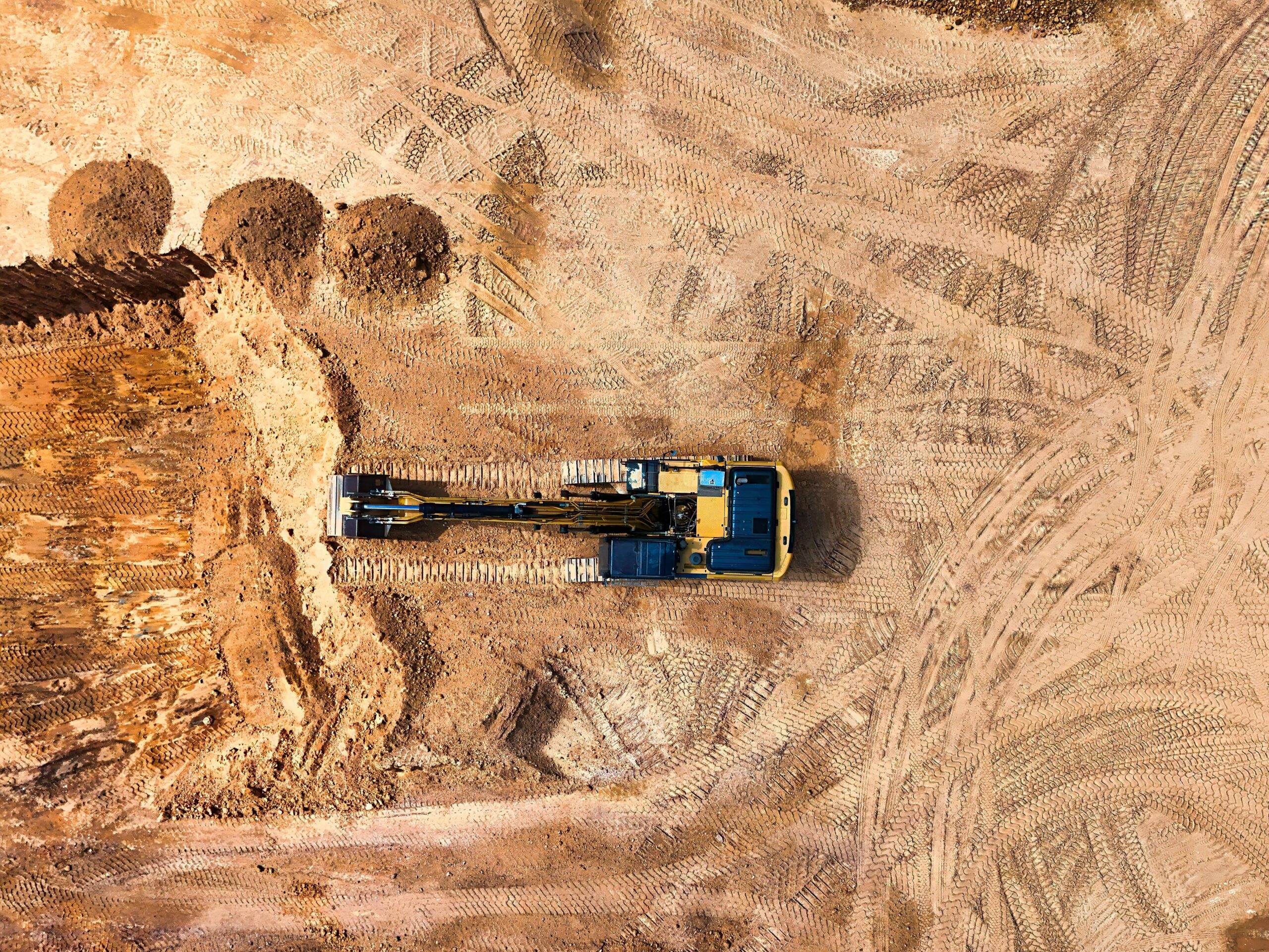 "A split-screen image showcasing construction machine control technology: on the left, a bulldozer leveling soil at a construction site under a clear sky; in the center, a digital display showing real-time 3D terrain data for machine control; on the right, an excavator performing precise grading work in a similar outdoor setting."