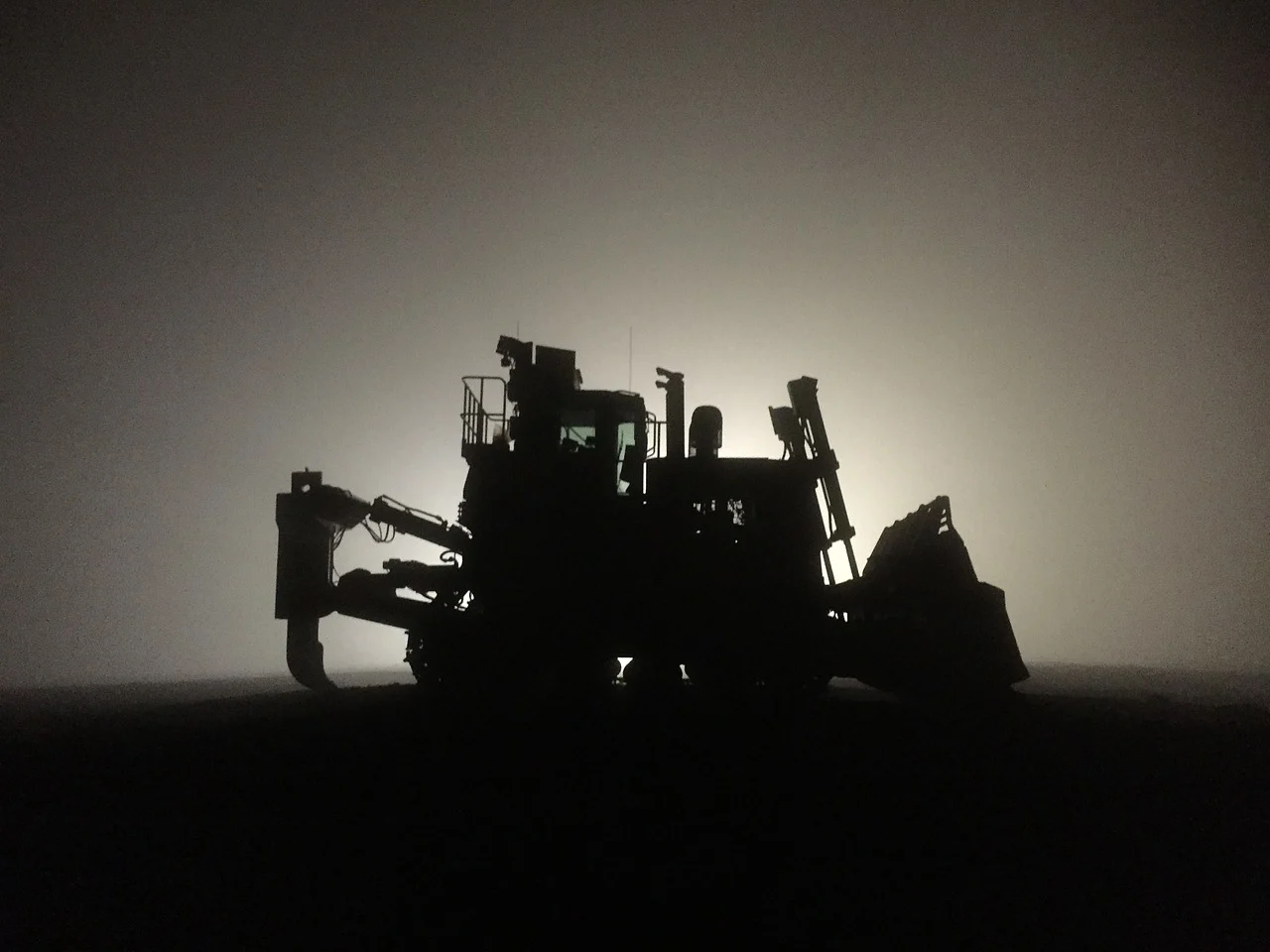 "A split-screen image showcasing construction machine control technology: on the left, a bulldozer leveling soil at a construction site under a clear sky; in the center, a digital display showing real-time 3D terrain data for machine control; on the right, an excavator performing precise grading work in a similar outdoor setting."